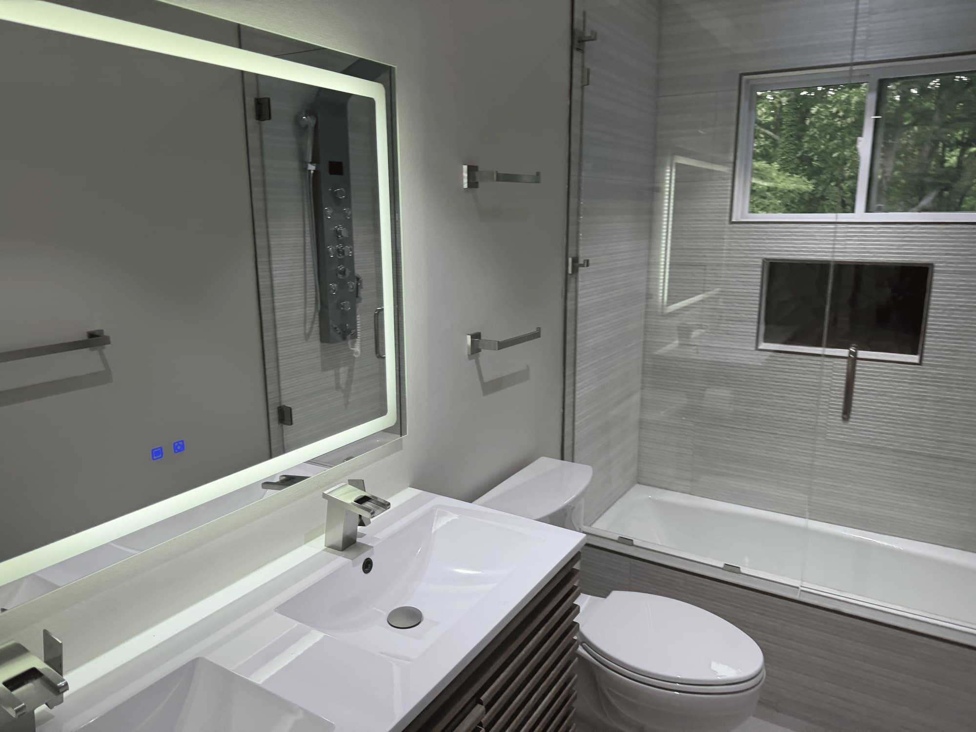 Modern bathroom with a backlit LED mirror and glass tub-shower after a clean