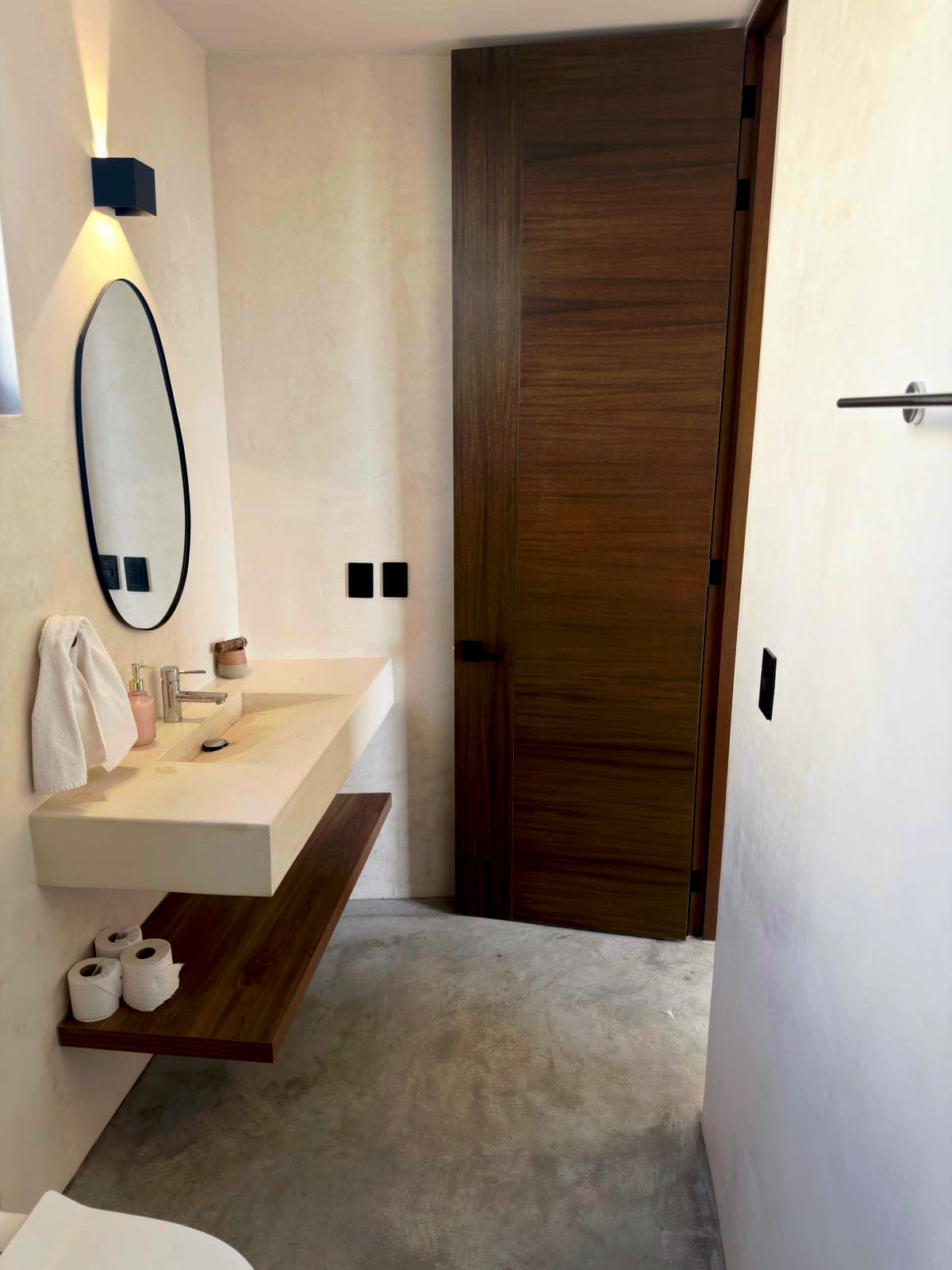Freshly cleaned bathroom with a floating vanity, a round mirror, and a walnut door in Norcross