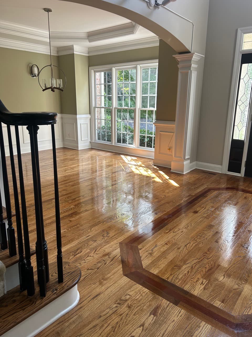 Foyer with freshly polished hardwood floors and an inlaid parquet border