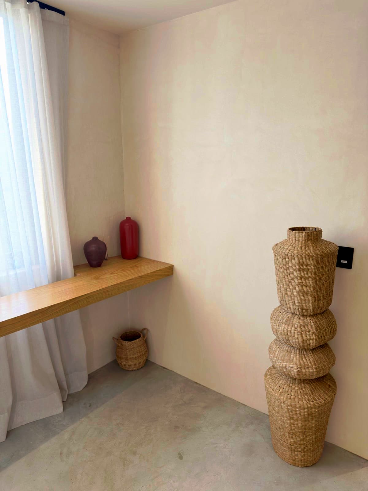 Freshly cleaned styled corner with a floating wood shelf, ceramic vases, and a woven basket in Roswell