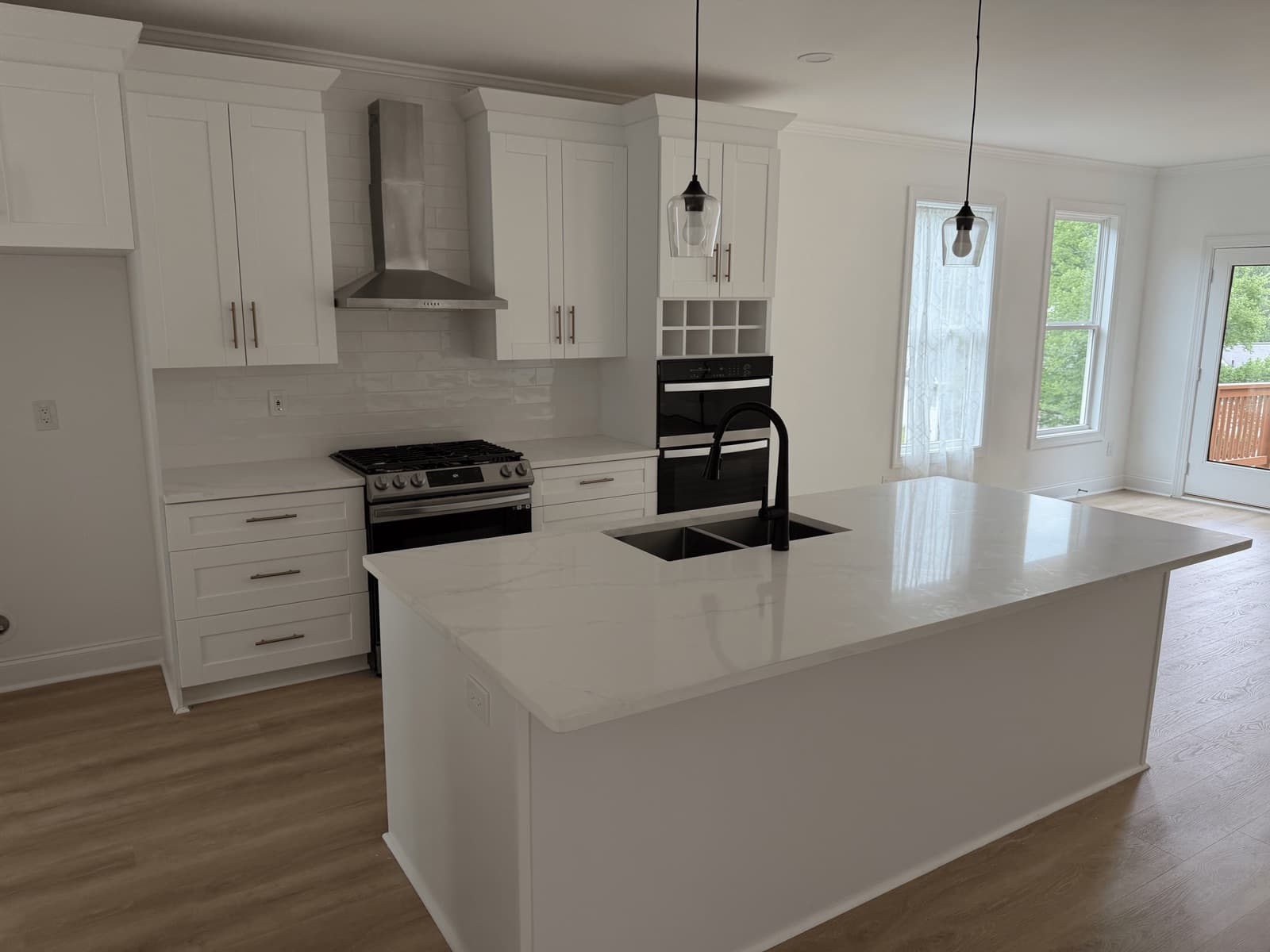 Empty kitchen with white cabinets and a quartz island after a move-out clean